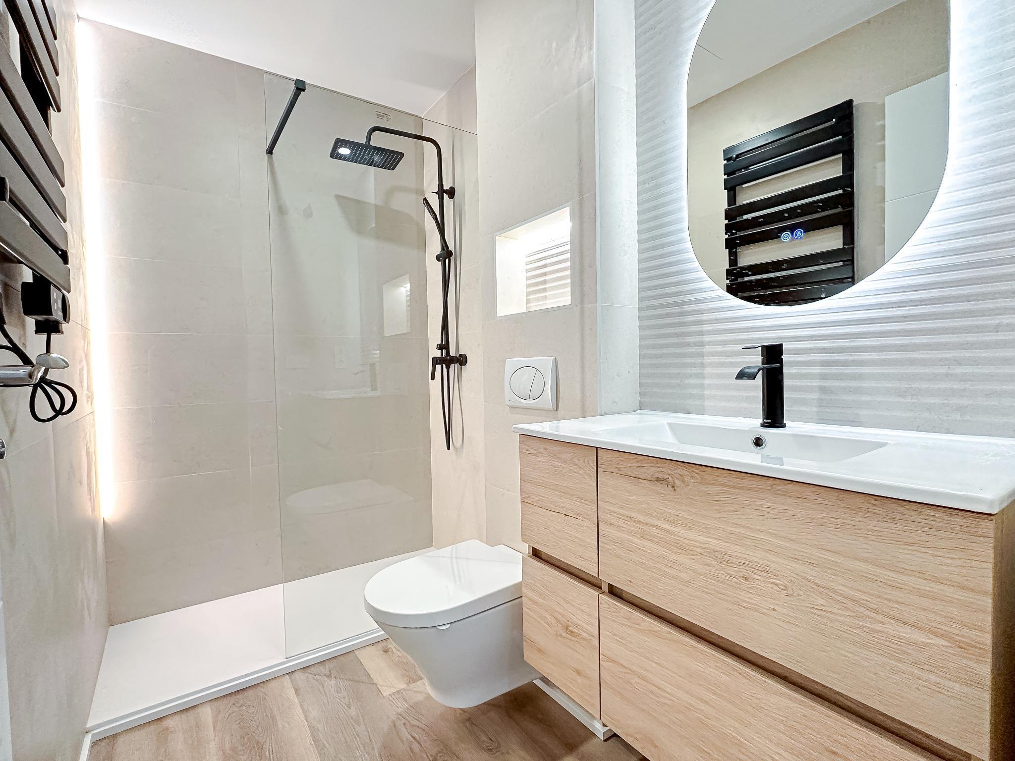 Baño reformado con madera y ducha de obra